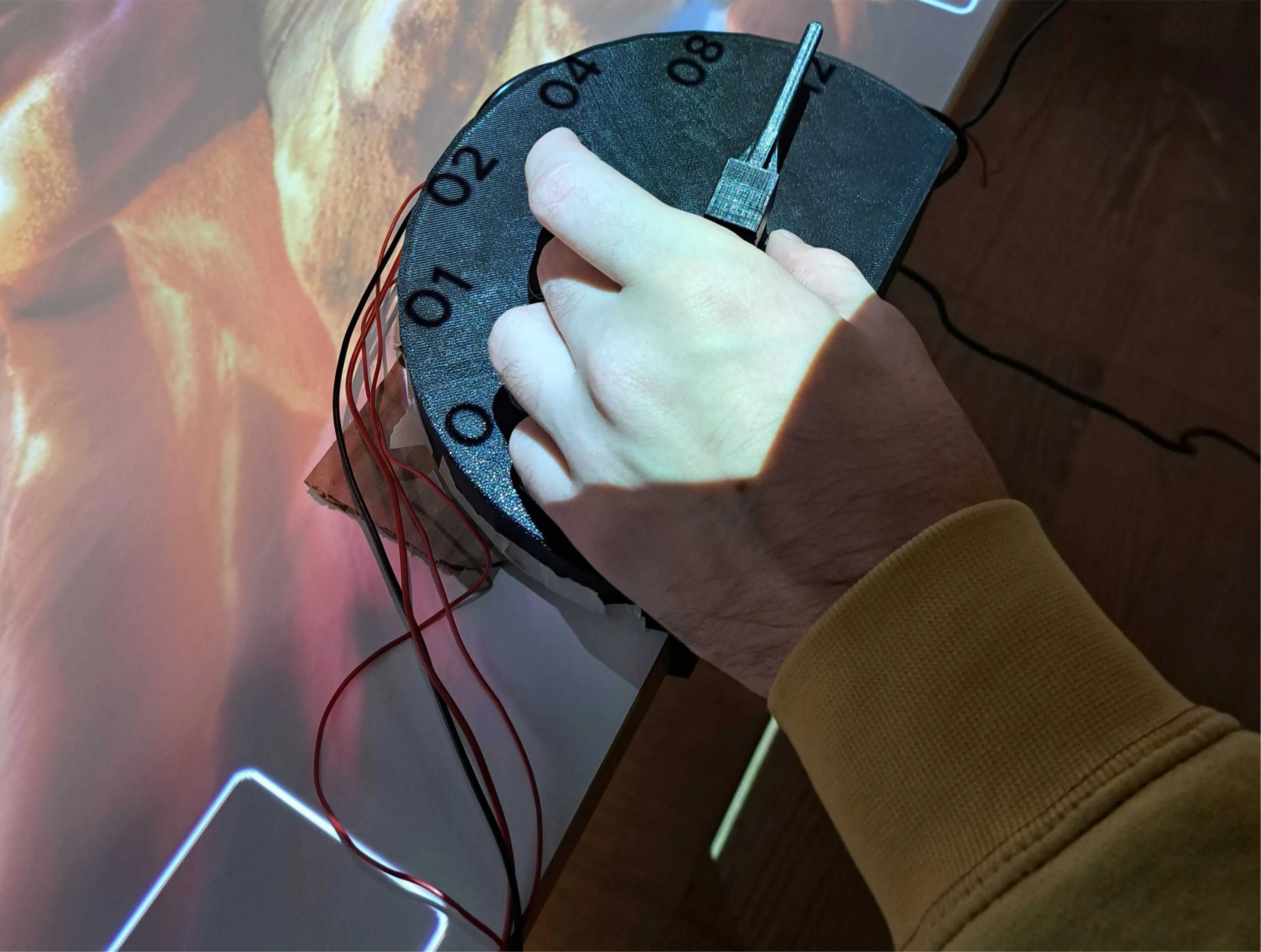 Assembled physical dial controller clamped onto the edge of the exhibition table with hidden wiring.