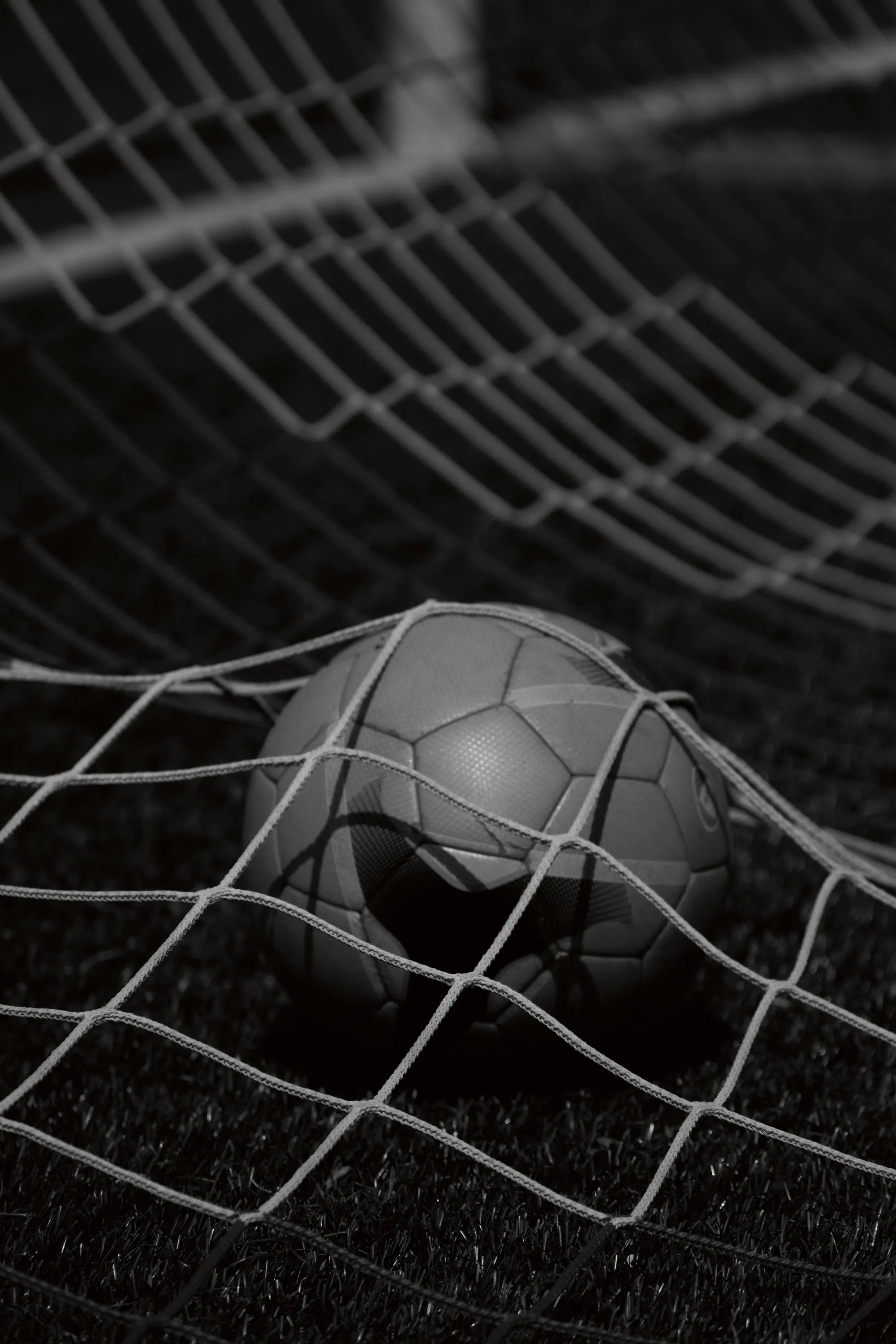 Close up in black and white of a ball inside of the goalnet