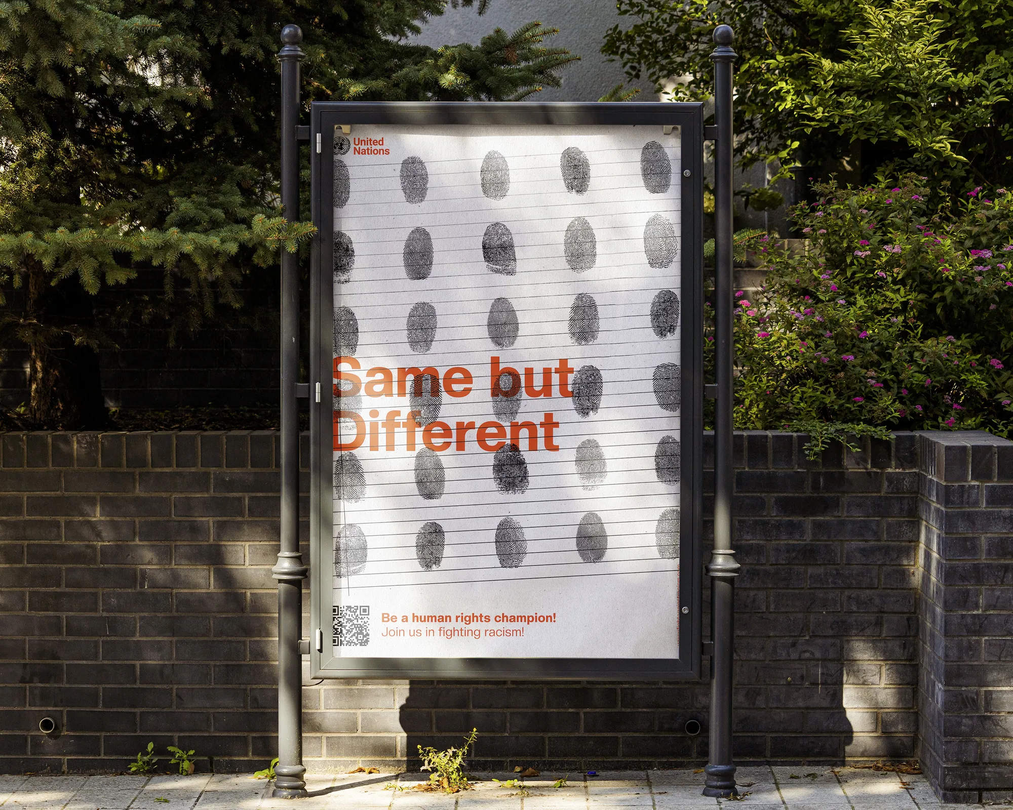 A poster in a street display case: a grid of black fingerprints on lined paper, above them the orange line 'Same but Different' and the United Nations logo.