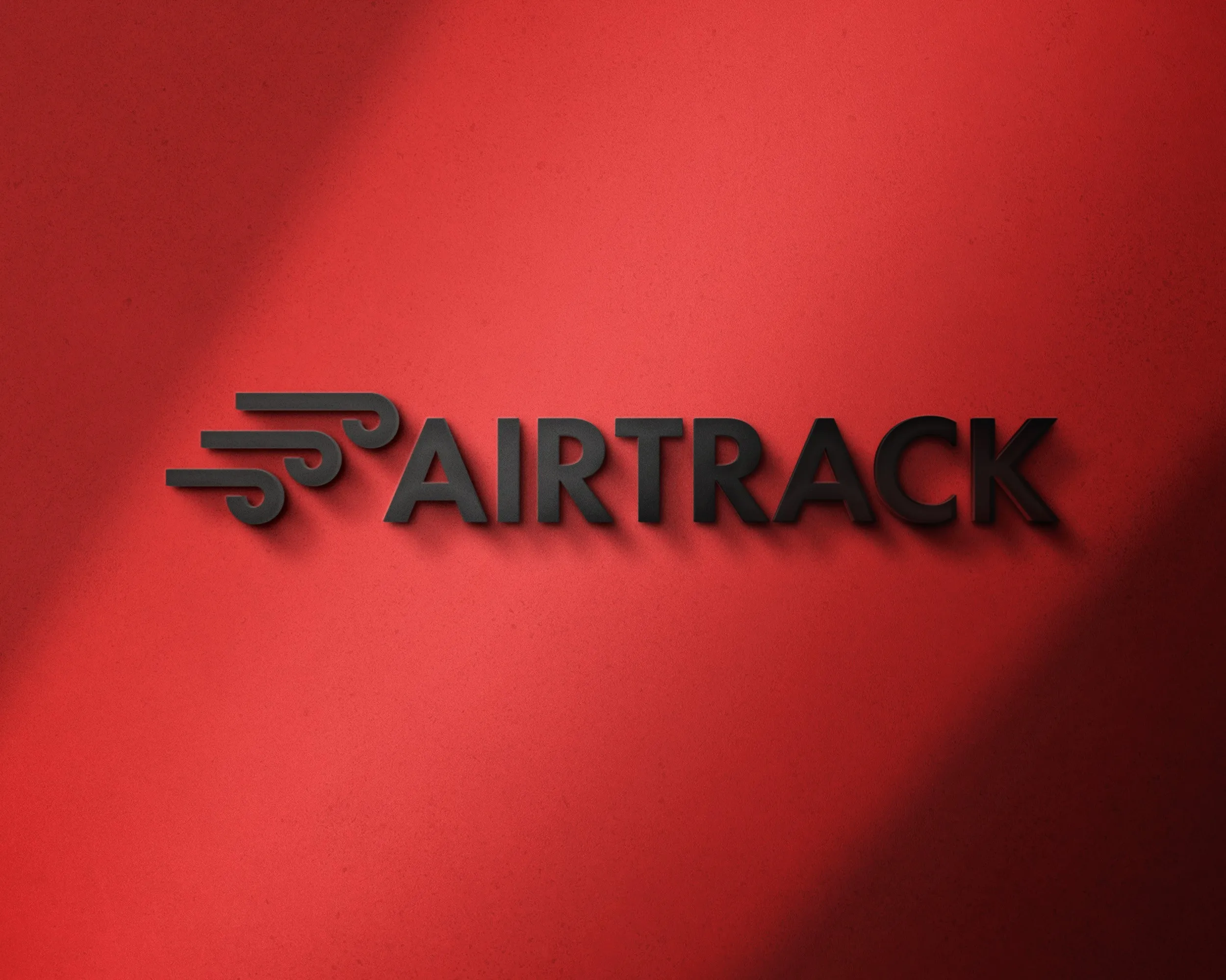 The 'Airtrack' logo on a red wall: a black wordmark with three stylised wind lines running ahead of it.